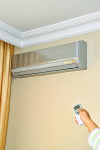 person holding remote to turn on ductless air handler