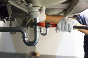 plumber-hands-working-on-plumbing-under-sink