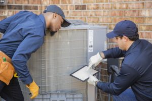 two-techs-working-on-ac-unit-with-clipboard