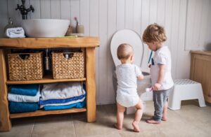 two-small-children-flushing-items-down-toilet