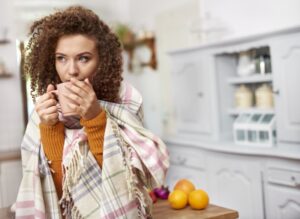 girl-huddled-in-blanket-drinking-out-of-mug