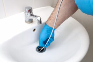 plumber-inserting-a-drain-snake-in-a-bathroom-sink