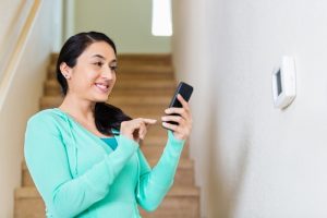 person-adjusting-thermostat-with-phone