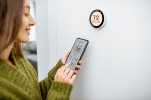person-setting-thermostat-with-smartphone